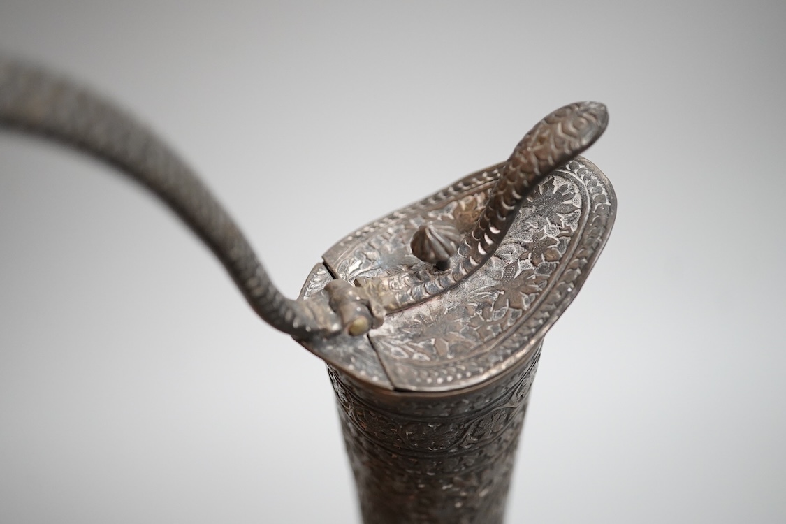 A late 19th century Indian white metal ewer, with extensive foliate decoration and cobra handle, height 30.3cm.